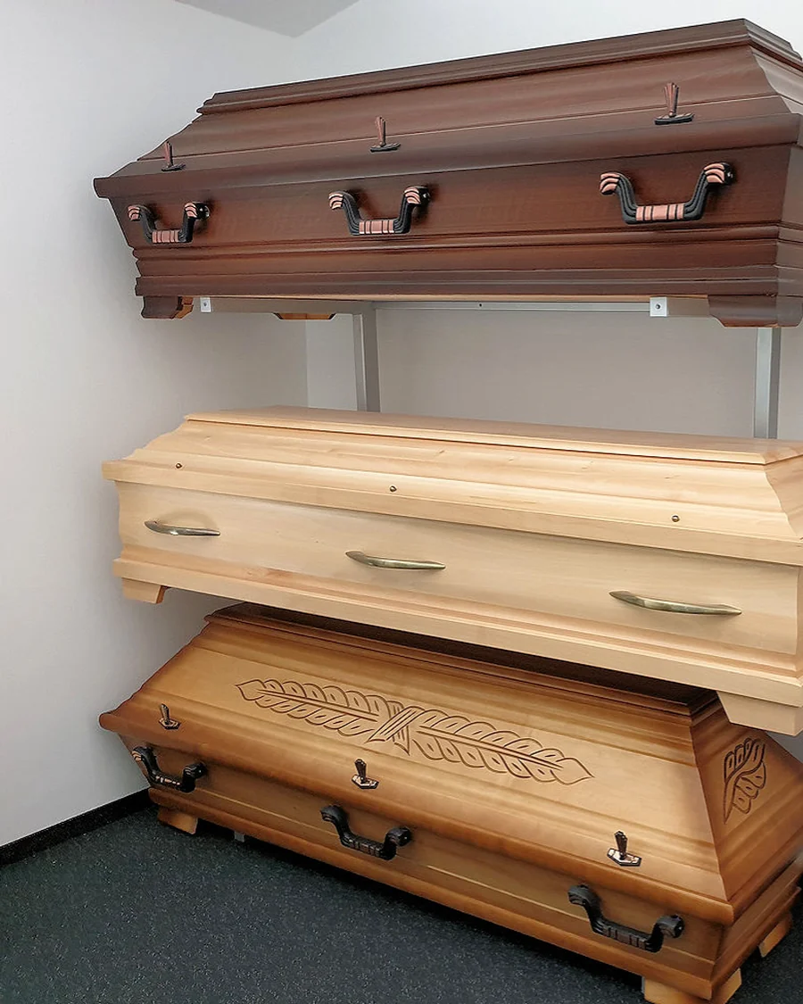 Drei Särge in der Ausstellung: dunkel profiliert, hell schlicht, Eiche mit geschnitzter Ähre