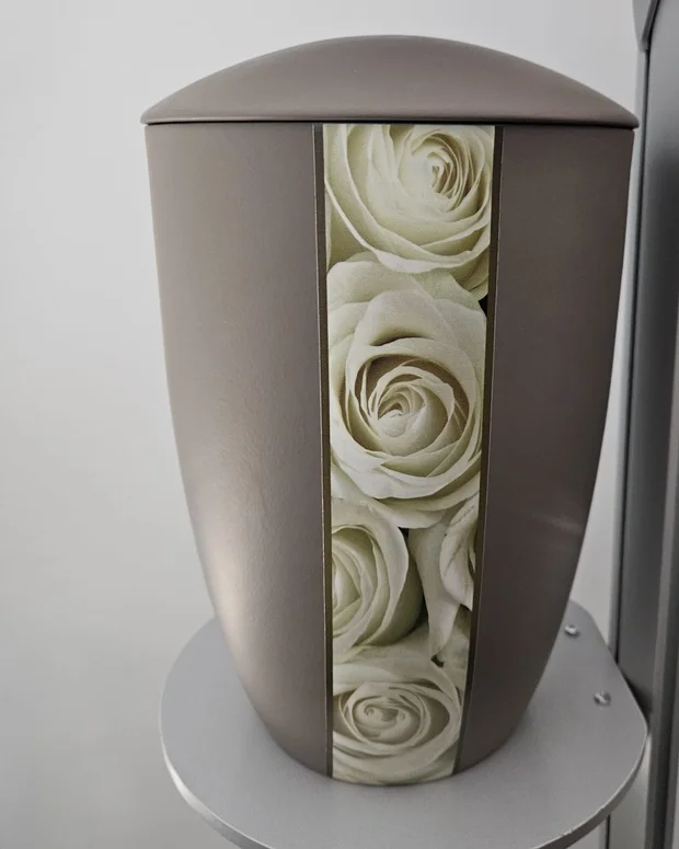Taupefarbene Urne mit einem senkrechten Band aus weißen Rosen