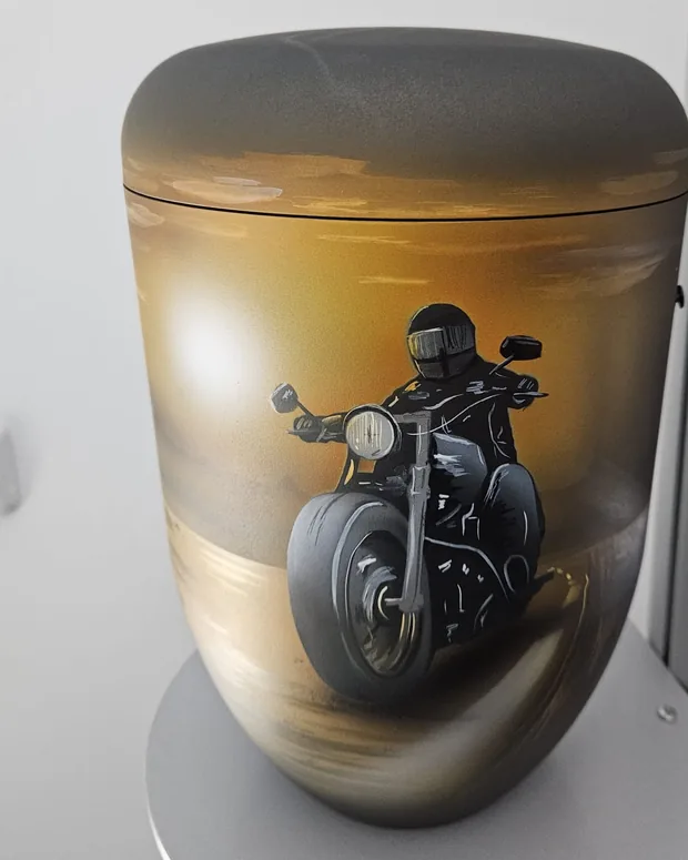 Urne mit gemaltem Motorradfahrer im Abendlicht