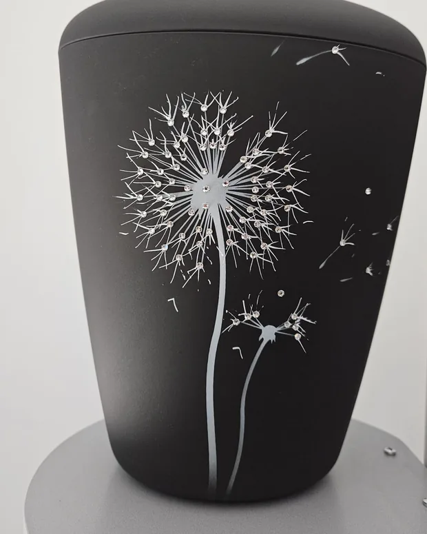 Schwarze matte Urne mit einer weißen Pusteblume