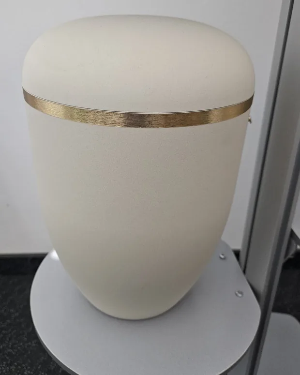 Cremeweiße Urne mit einem goldenen Band